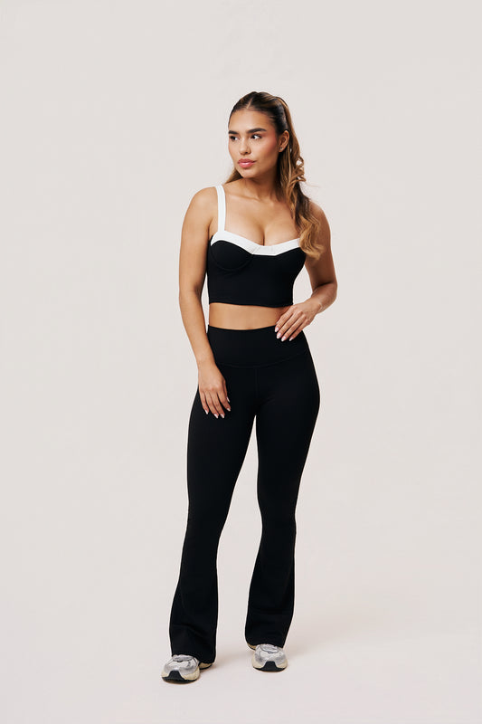 Woman wearing a black sports bra and leggings on a white background
