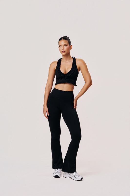 Woman wearing a black athletic outfit on a light gray background